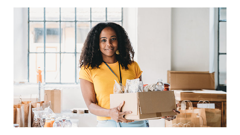 Volunteer woman holding a box of food and drinks